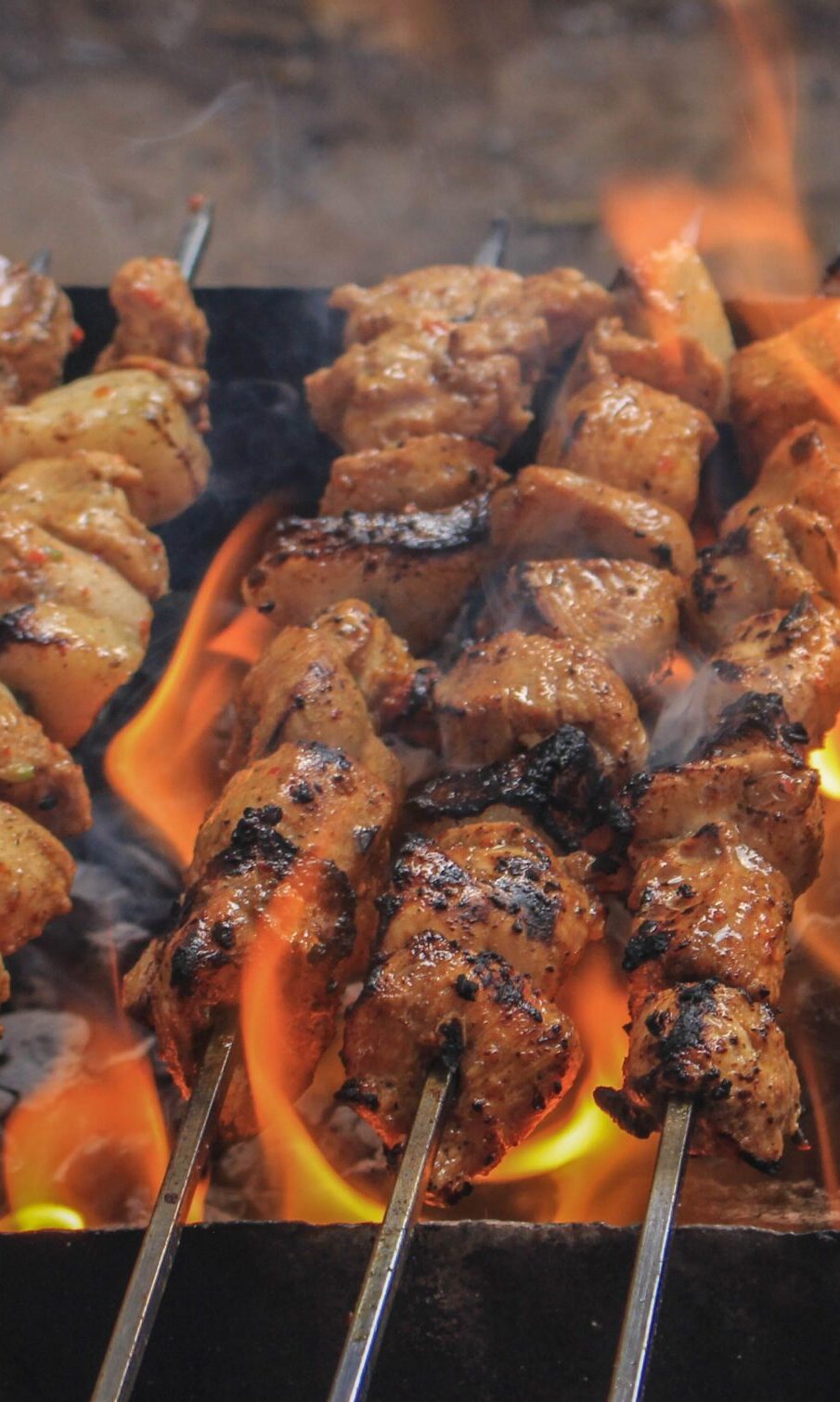 Juicy skewers of grilled meat sizzling over open flames, creating a tasty barbecue feel.