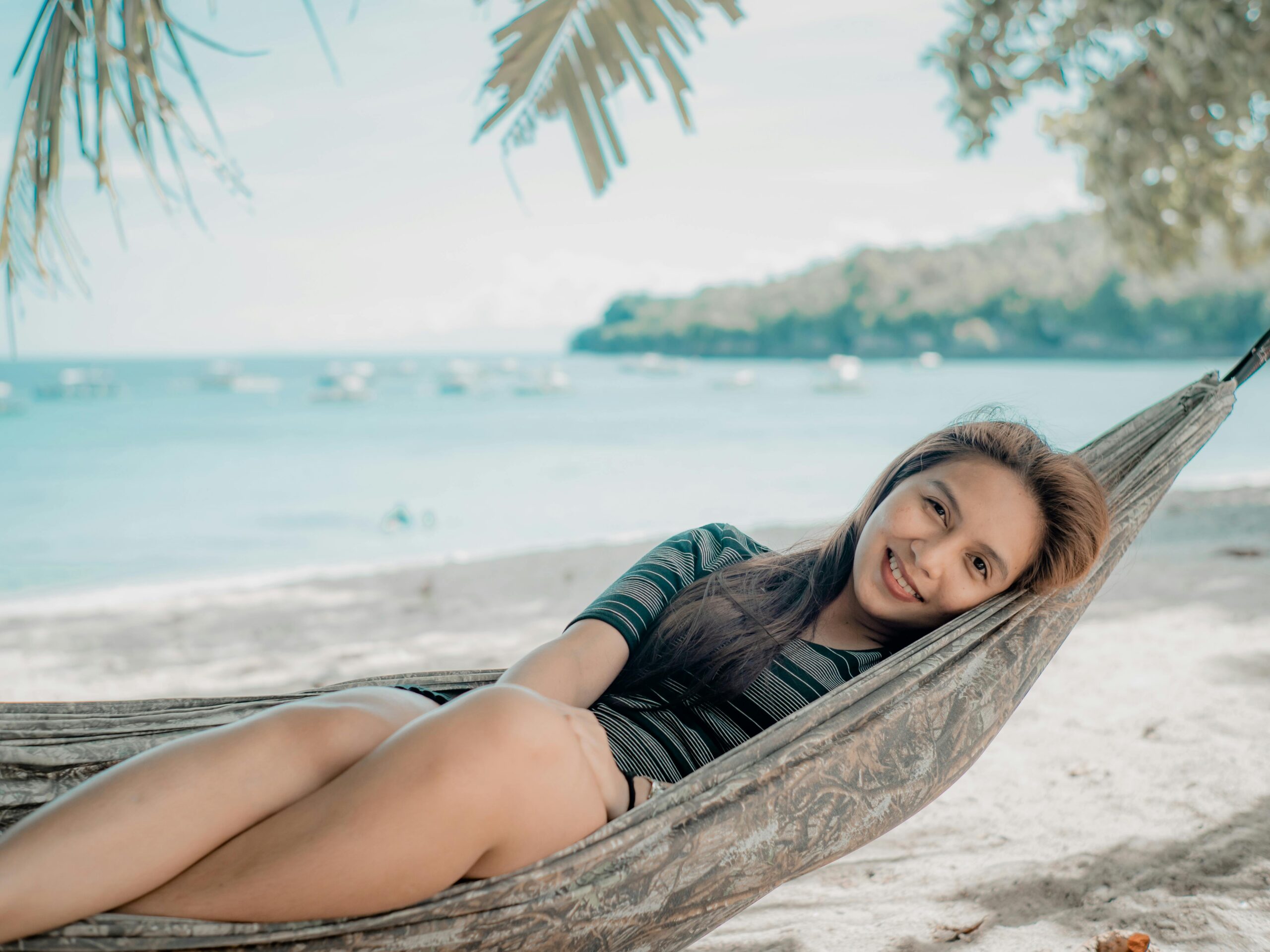 A woman relaxing in a hammock by the beach in Davao, enjoying a peaceful sunny day.