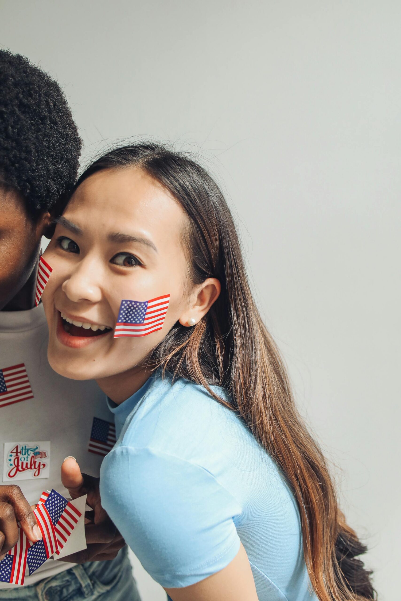 Young adults celebrating 4th of July with American flag face paint, exuding joy and patriotism.
